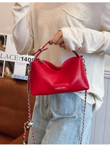 Minimalist red faux leather handbag with a metal chain strap shown in a lifestyle setting