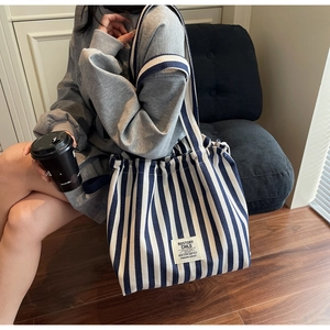 Close-up of blue and white striped canvas tote bag with woven brand label detail