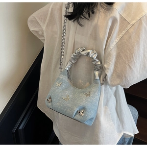 Dettaglio della borsa in denim celeste con farfalle argentate e tracolla a catena
