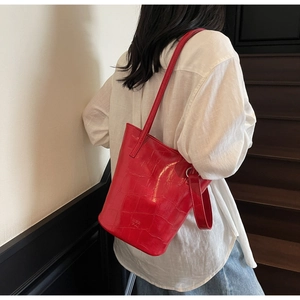 Close-up of red oil wax leather bucket bag with crocodile pattern texture and shoulder strap