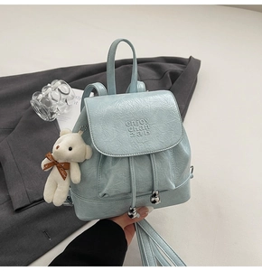 Detail showing mint blue glossy bucket backpack with plush bear and drawstring close