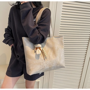 Close-up of minimalist beige tote bag with H.SHAN logo and a cute teddy bear charm
