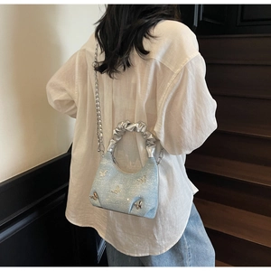 Detail of light blue glitter dumpling bag with 3D silver butterflies and pleated handle