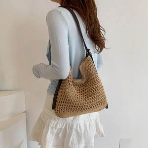Detail of woven straw hobo bag with dark brown leather strap and cotton lining