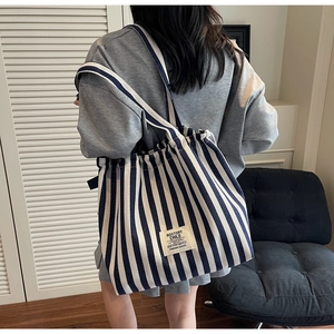 Detail of blue and white striped canvas tote bag with shoulder strap in a home setting