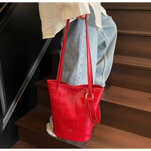 Detail of red wax leather bucket bag with crocodile texture and metal ring buckle