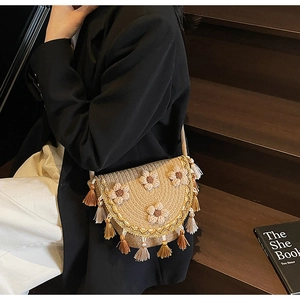 Detailed close-up of woven bucket bag featuring floral accents and fringe tassels