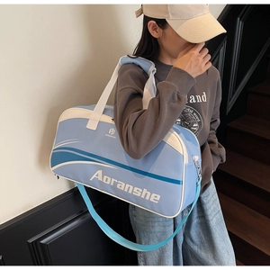 Detail of adjustable shoulder strap and logo on a blue and white sports gym bag