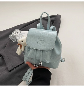 Detail of light blue bucket backpack with PU leather texture, bear charm, and silver beads