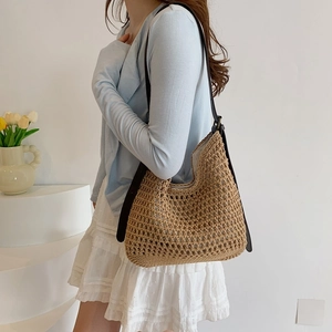 Detail of hand-woven straw tote bag with mesh pattern and black leather strap