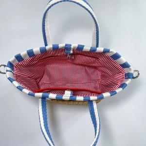 Internal view of the straw tote bag with striped lining and zippered inner pocket