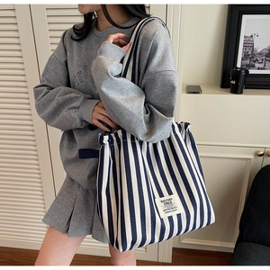 Detailed shot of a blue and white striped canvas tote bag worn on the shoulder
