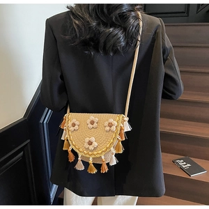 Detail of hand-woven straw crossbody bag with 3D floral accents and tassel trim decoration