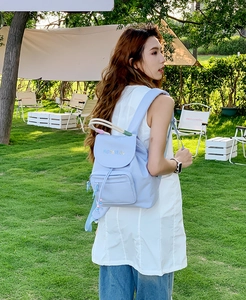 Detail of light blue nylon backpack with MOFANLUO logo and drawstring in camping scene