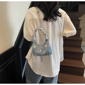 Detail of blue denim hobo bag with silver butterfly charms and metallic pleated handle