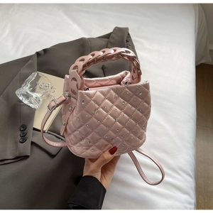 Dettaglio della borsa a secchiello rosa trapuntata con strass argento e manico intrecciato