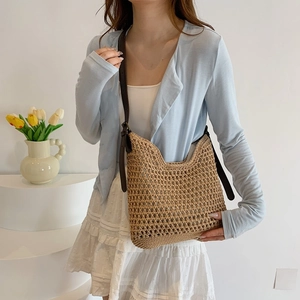 Detailed shot of a hand-woven straw tote bag with brown leather shoulder straps