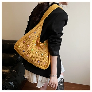 Close-up of yellow knit tote bag featuring colorful faux pearls and crochet texture