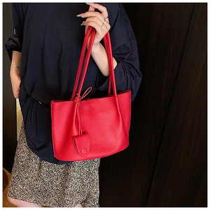 Close-up of red lychee texture tote bag with matching coin purse worn by a model