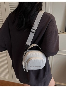 Light grey canvas crossbody bag with adjustable wide strap and front zipper pocket