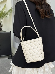 Elegante borsa a secchiello beige trapuntata con borchie argento e tracolla a catena