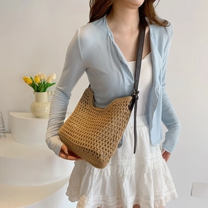 Detailed texture of hand-woven straw tote bag with brown leather shoulder strap