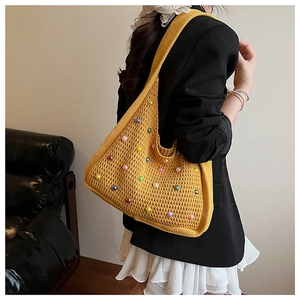 Detail of yellow knit tote bag featuring colorful translucent beads and wide shoulder straps