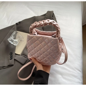 Dettaglio della borsa a secchiello rosa trapuntata con strass e manico intrecciato