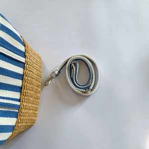 Detail of blue striped canvas and straw woven tote with adjustable shoulder strap hooks