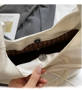 Dettaglio della chiusura magnetica e fodera a righe della borsa in pelle bianca