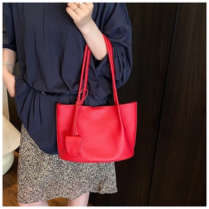 Detailed close-up of red lychee pattern leather tote bag with elegant hanging ornament