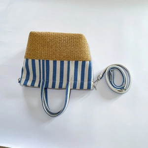 Detail of canvas stripe and straw woven patchwork tote with detachable metal buckle strap