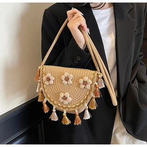 Detail of woven straw bucket bag with crochet flowers and colorful tassels for summer