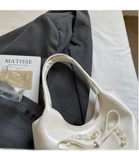 Dettaglio della borsa tote in PU bianco panna con pizzo e fiocco in scena lifestyle