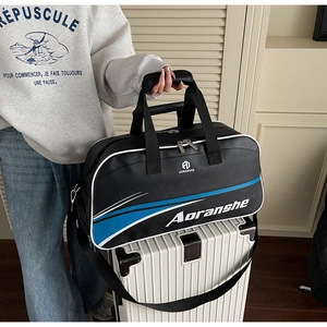 Detail of waterproof black travel bag with blue stripes sitting on a white suitcase