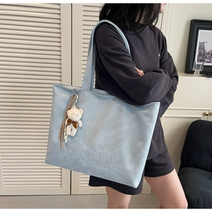 Detail of light blue tote bag with H.SHAN embossed logo and a cute bear charm
