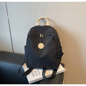 Close-up of black nylon backpack with tan leather handle and multi-pocket design detail
