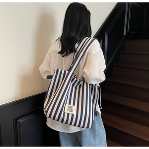 Detail of blue and white striped canvas tote bag showing the branded logo patch