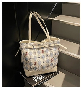 Dettaglio della borsa tote con motivo a rombi blu, orsetti rossi e manici in ecopelle bianca