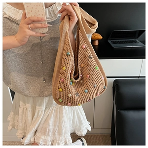 Detail of khaki knitted tote bag with colorful beads shown on model in indoor setting