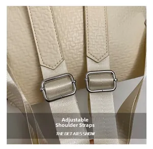 Detail of adjustable nylon strap and metal buckle on cream faux leather backpack
