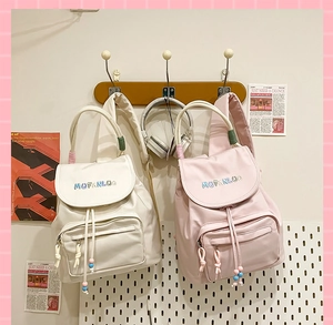 Detail of embroidered backpacks with drawstring closures in white and pink color options