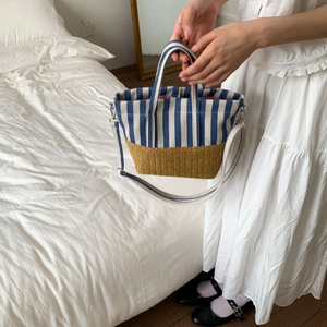 Detail showing blue and white striped canvas and woven straw texture on tote bag
