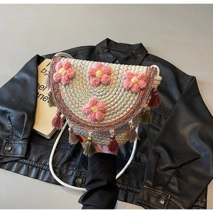 Close-up of woven crossbody bag with pink floral accents and colorful tassels on leather