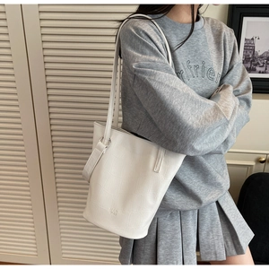 Close-up of a white crocodile embossed bucket bag featuring a slender shoulder strap