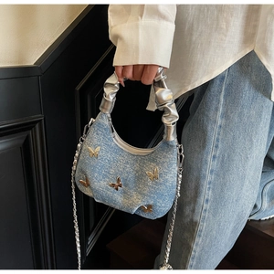Detail of light blue denim hobo bag with silver butterfly studs and scrunchie handle