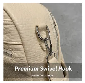 Close-up of silver metal hook and pebble grain leather texture on off-white backpack