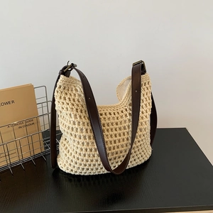 Detail of beige crochet woven tote with brown leather strap on a minimalist wooden table