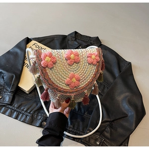 Close-up of bohemian woven bucket bag featuring 3D pink flowers and colorful tassels