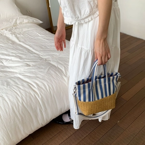 Detail view of canvas striped tote with woven bottom and adjustable white strap